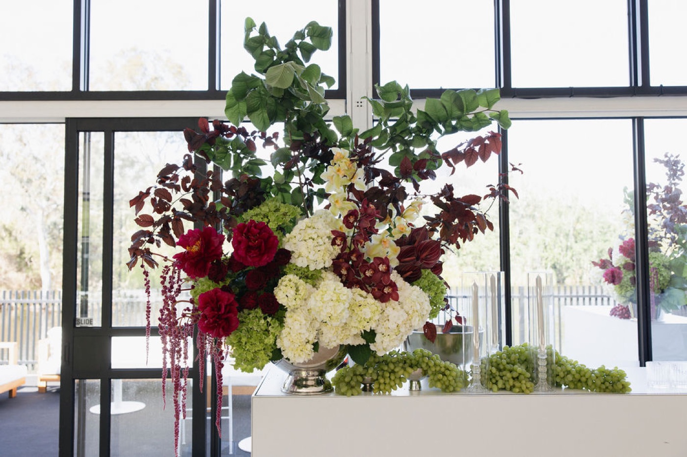 A tall floral arrangement against a glass wall