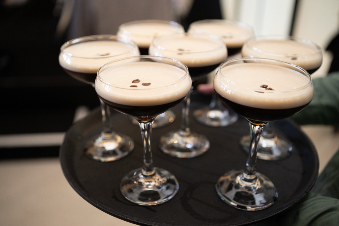 A tray of espresso martinis, coffee beans resting on the foam