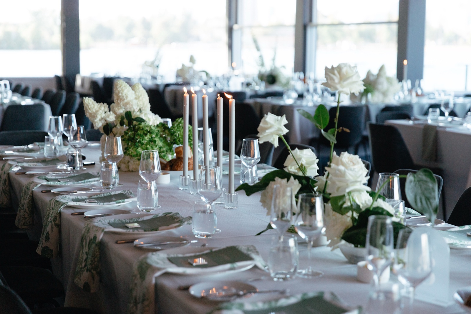 A long table dressed with white florals and tall candles